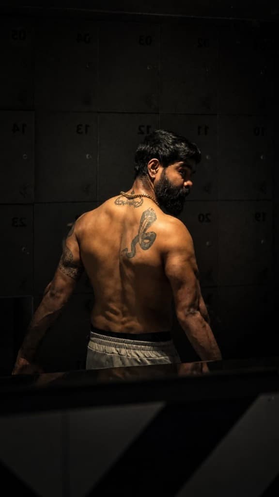 Side pose highlighting physical condition and traditional cobra tattoo